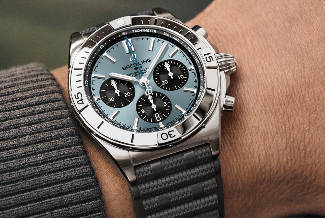 A close-up at a gentleman’s wrist wearing a silver watch with a light blue dial and three black subdials.