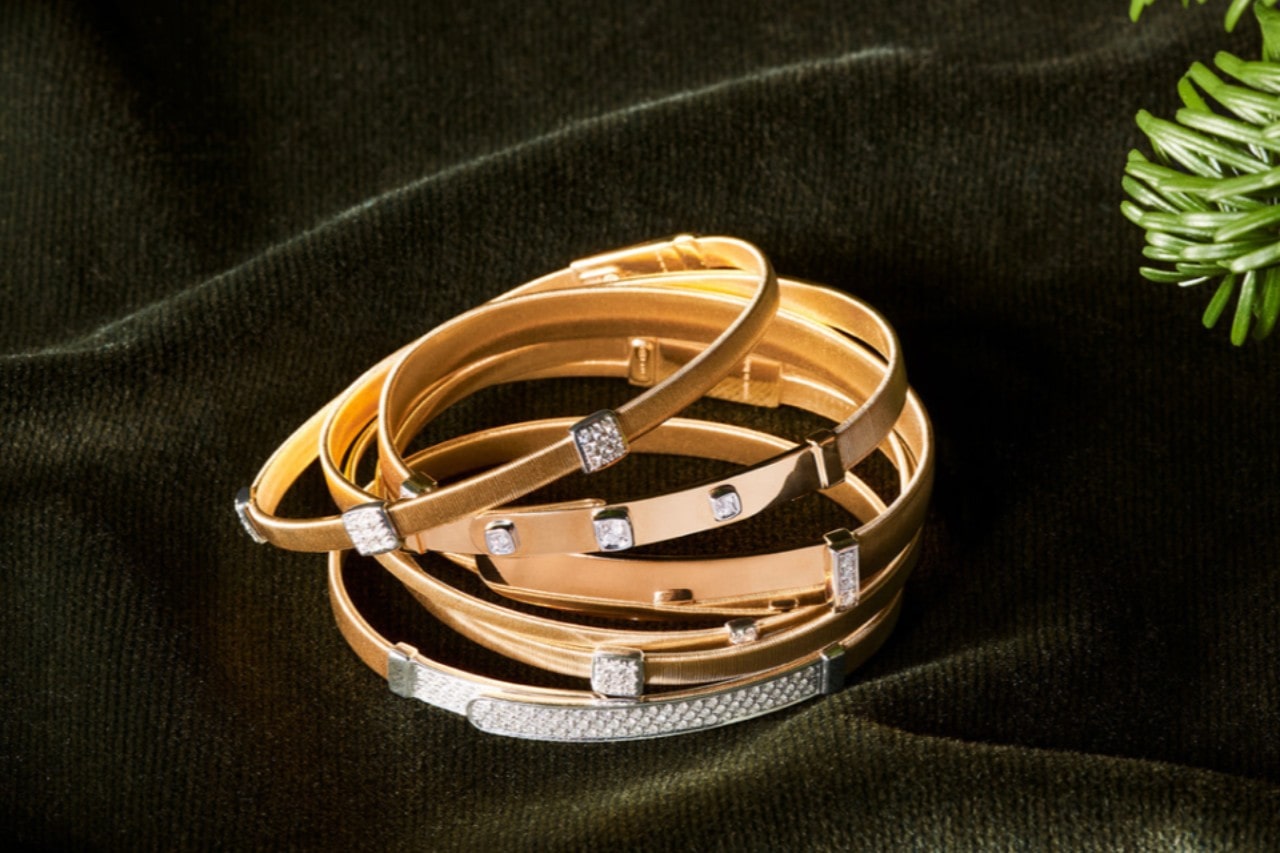 a stack of mixed metal bangle bracelets with diamond accents on a green velvet surface