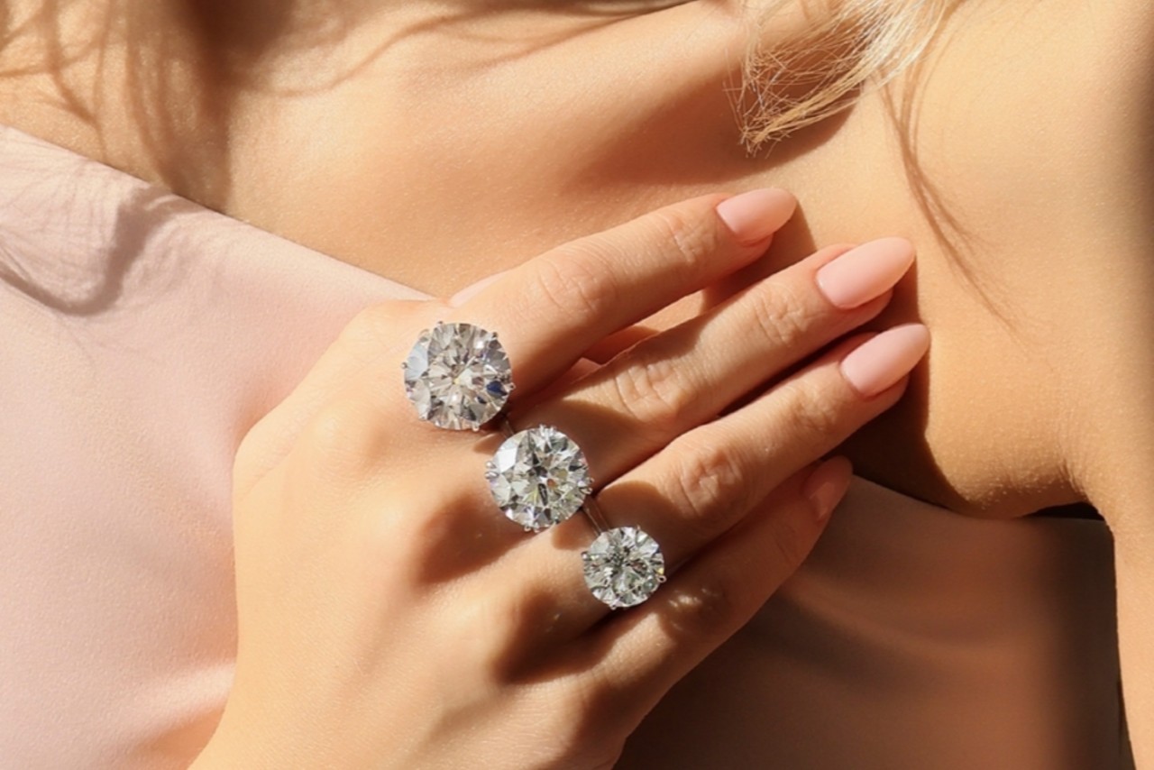 a woman wearing three diamond solitaire rings with large diamonds a woman wearing three diamond solitaire rings with large diamonds