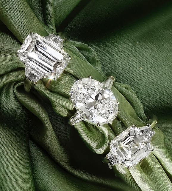 three engagement rings with large diamonds on green fabric three engagement rings with large diamonds on green fabric
